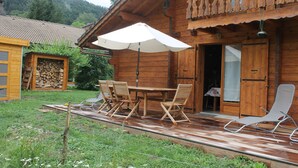Una cabaña de madera con un patio, una mesa y sillas, y una sombrilla.