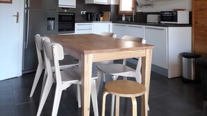 A modern kitchen with white cabinets, a wooden dining table, and four chairs.