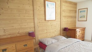 A wooden-paneled room with a bed, a dresser with animal drawer knobs, a lamp, and a framed picture on the wall.