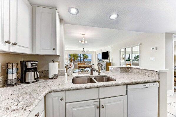 A kitchen with white cabinets, a double sink, and a coffee maker.