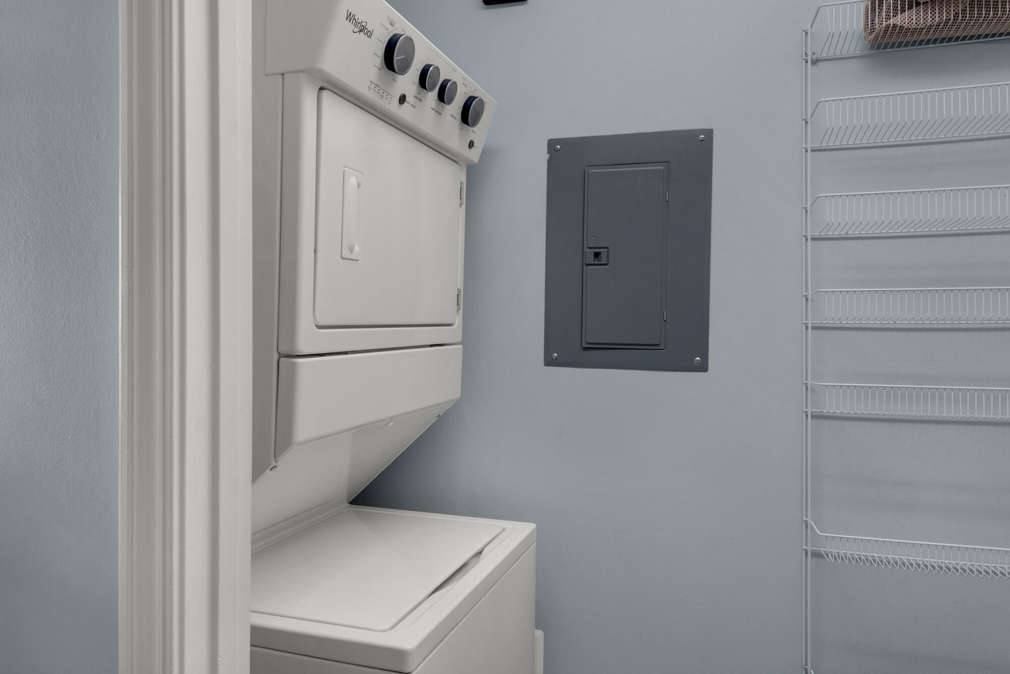 Une buanderie équipée d’un lave-linge et d’un sèche-linge, une pièce utilitaire avec une porte et une étagère métallique.