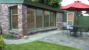 A patio with a brick building, a red umbrella, and outdoor furniture.