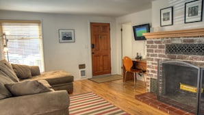 A living room with a fireplace, a sofa, a striped rug, and a door.