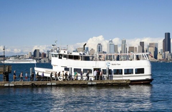 A white ferry with "World Taxi" written on the side, docked at a pier with people boarding and disembarking.
