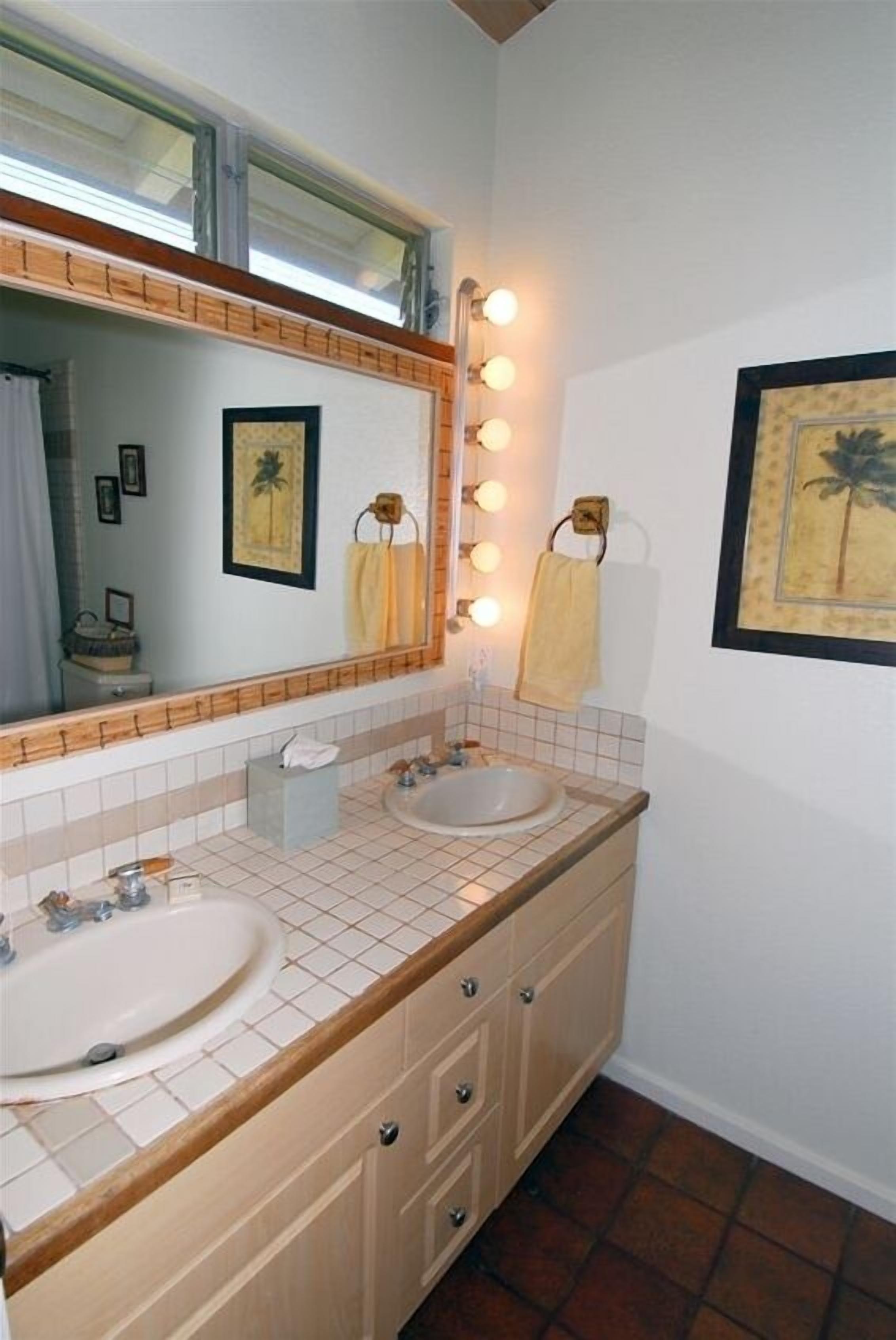 Un baño con dos lavamanos, un espejo grande y luces en la pared.