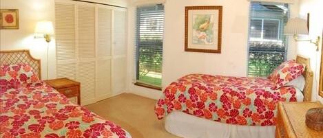 Un dormitorio con dos camas, un ventilador de techo y una ventana con persianas.