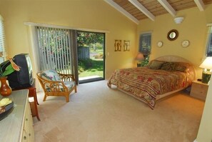 A bedroom with a bed, a chair, a desk, and a window with blinds. - Gorgeous Greenbelt!  Home with beautiful mountain views & 5 min walk from beach! (Koloa)