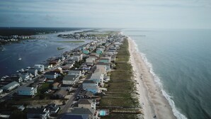 Vista aérea de uma área residencial costeira com casas, uma praia e um cais.