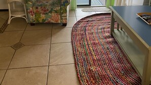 Uma sala de estar com um sofá, uma mesinha, um abajur e um tapete colorido.