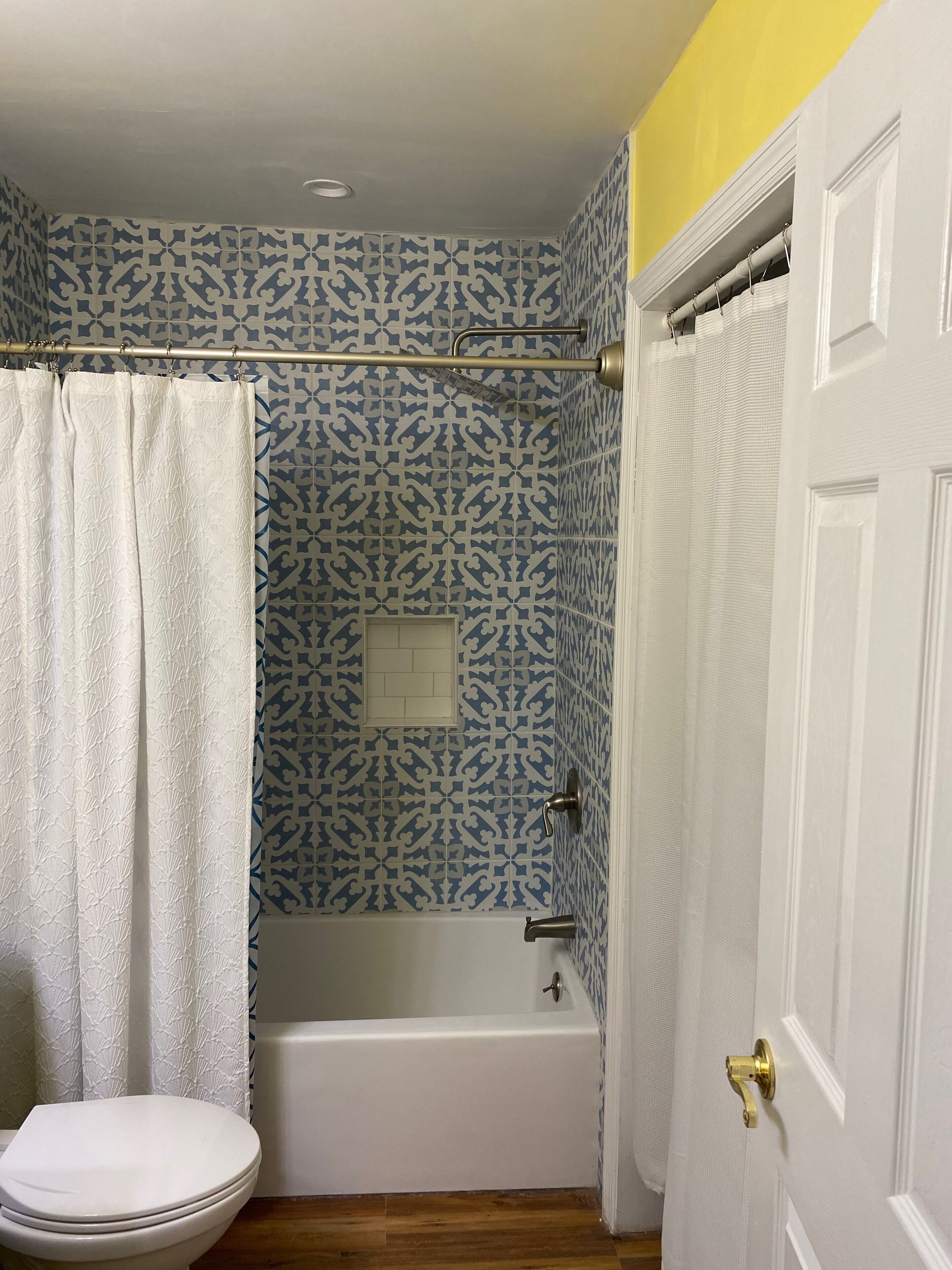 Une salle de bain avec un mur à motifs, une baignoire, des toilettes et un rideau de douche.