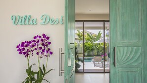 Entrada a una villa con un cartel que dice "Villa Desi" y vistas a la zona de la piscina.