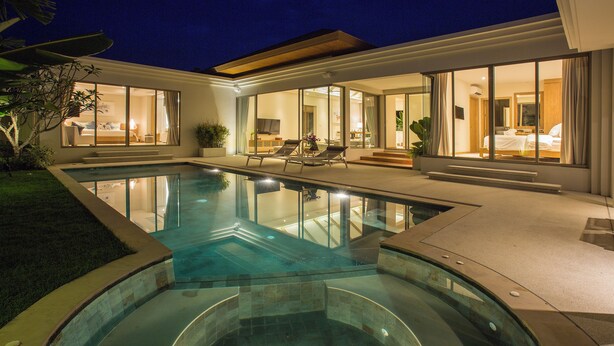 Una casa moderna con piscina, amplias puertas de vidrio y un interior luminoso.