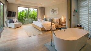 Un dormitorio moderno con una cama grande, una zona de estar, una bañera y un televisor.