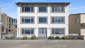 A multi-story building with a flat roof, large windows, and a central entrance with a door. - Right on the Famous Mission Beach Boardwalk - Sleeps up to 10 on Ground Floor - Best location in Mission Beach (San Diego)