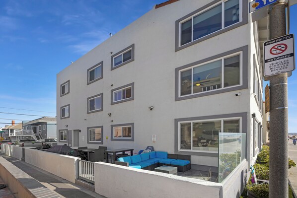 A multi-story building with large windows, a gated patio area with outdoor furniture, and a 'No Motorized Vehicles' sign.