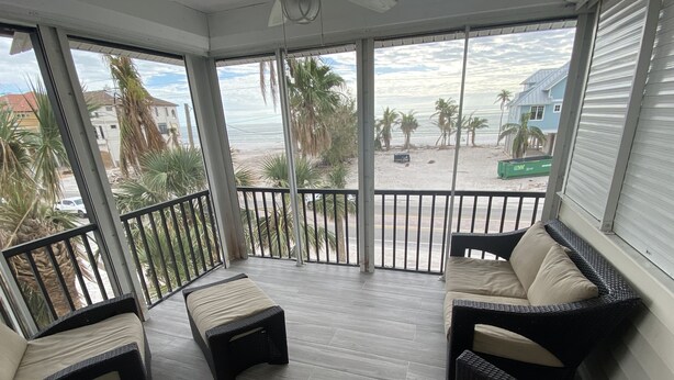 Un balcón techado con muebles de mimbre y vista a la playa.