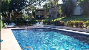 Une piscine rectangulaire à l’eau d’un bleu cristallin, entourée de chaises longues et d’une clôture.