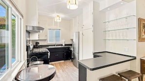 A modern kitchen with a central island, a dining table, and a glass wine rack.