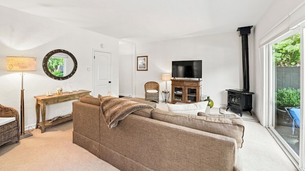 A living room with a sofa, a television, a fireplace, and a large window.