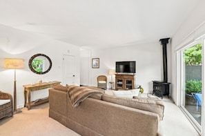 A living room with a sofa, a television, a fireplace, and a large window.