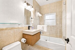 Une salle de bain avec une douche à parois de verre, un meuble-lavabo en bois, des toilettes et un grand miroir.