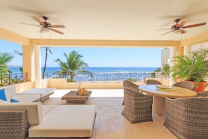 Varanda com mobiliário de vime, uma mesa e vista para o oceano.