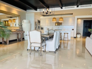 Uma cozinha ampla com eletrodomésticos modernos, uma sala de jantar com uma mesa grande e cadeiras, e um piso lustroso.
