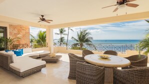 Ein geräumiger Balkon mit Korbmöbeln, einem runden Tisch und Blick aufs Meer.