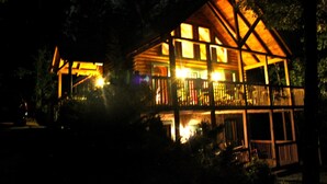 A wooden cabin with a balcony, surrounded by trees.