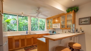 A kitchen with wooden cabinets, a white countertop, a built-in microwave, and a ceiling fan.