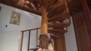 Una escalera en espiral de madera con una estatua de Buda en la parte inferior.