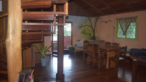 Un comedor de madera con ventilador de techo, una mesa, sillas y una planta en maceta.