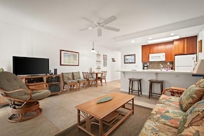 A living room with a TV, wicker chairs, a wooden coffee table, and a sofa.