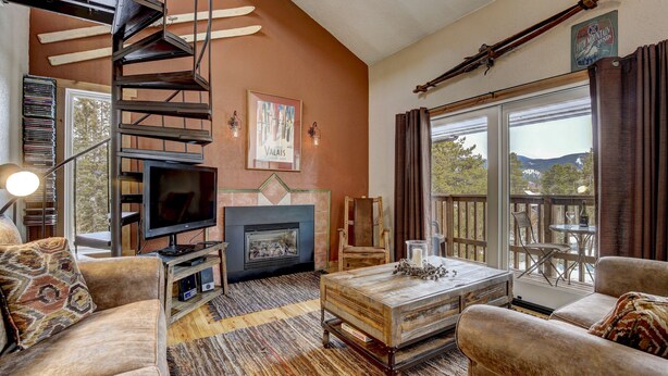 Una sala de estar acogedora con chimenea, televisor y una escalera que sube a un nivel superior.