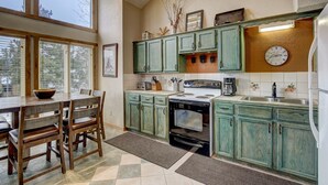 Una cocina con armarios de madera, una estufa y un comedor con sillas y una mesa.