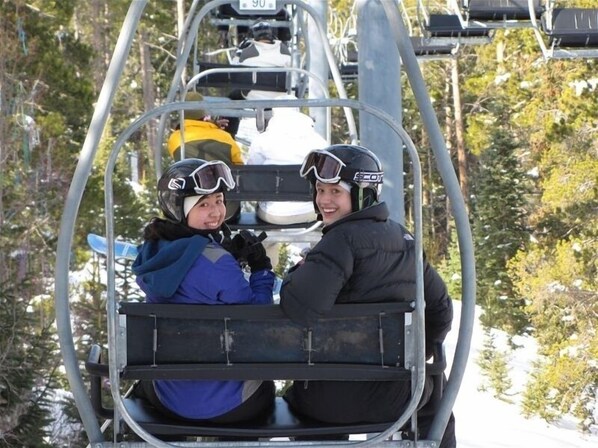 A ski lift with two passengers wearing helmets and ski gear.