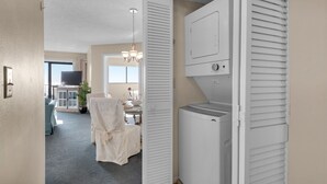 A laundry room with a white dryer, a ceiling fan, and a small table with a potted plant.
