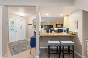 A modern kitchen with granite countertops, a black refrigerator, and wooden cabinets. There is a small bar area with two stools and a decorative wall piece. - Large Lovely 4bd, 3bth condo. Great family & couples place. Fall Discounts! (Branson)