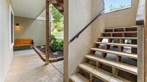 Eine Holztreppe mit Geländer, eine Holzbank und ein kleiner Gartenbereich mit Pflanzen und einem Weg.