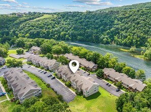A residential area with multiple houses, a parking lot, and a river in the background. - Beautiful 4bd, 3bth Condo, October weekends - Fall Color in Ozarks - So Lovely (Branson)