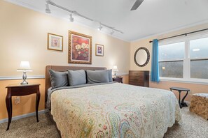 A bedroom with a large bed, two bedside tables, a dresser, a window with curtains, and wall-mounted artwork. - Beautiful 4bd, 3bth Condo, October weekends - Fall Color in Ozarks - So Lovely (Branson)