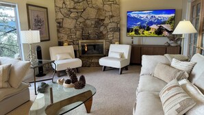 Una sala de estar acogedora con chimenea de piedra, asientos cómodos y un televisor grande.