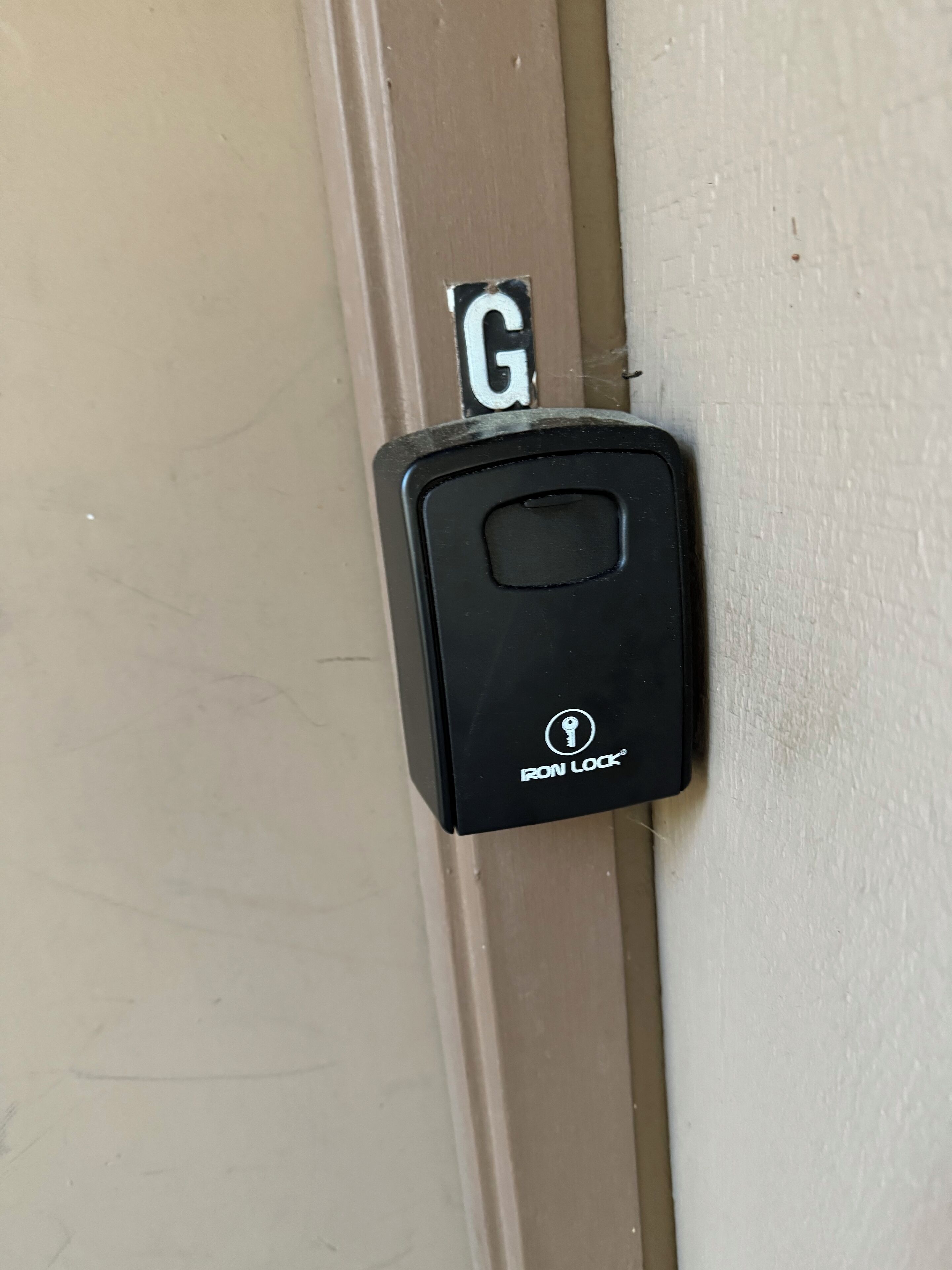 A black intercom with a keyhole and the brand name "IRON LOCK" on a beige door.