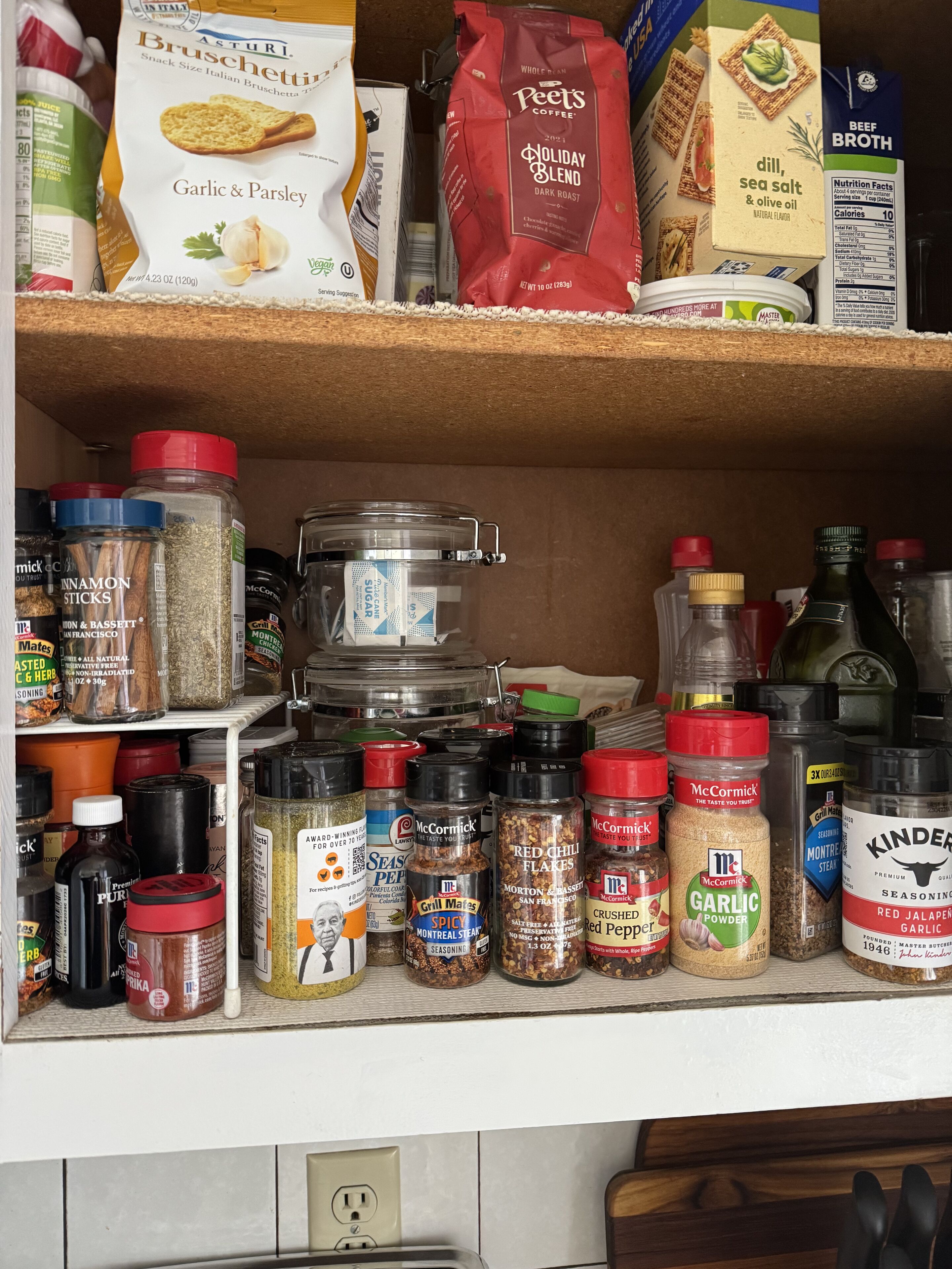 A kitchen shelf stocked with various spices, seasonings, and condiments.