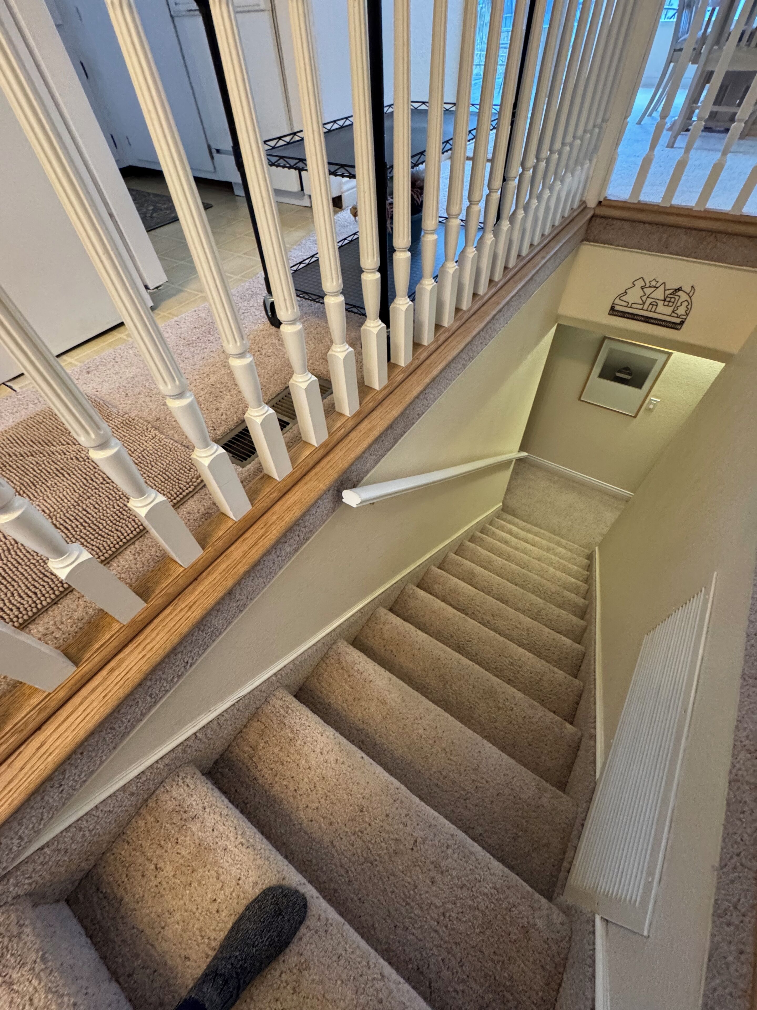 Eine Teppichstufen-Treppe mit weißen Balustern und einem hölzernen Geländer.
