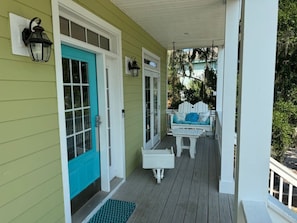 A porch with a blue door, white railings, and a bench.