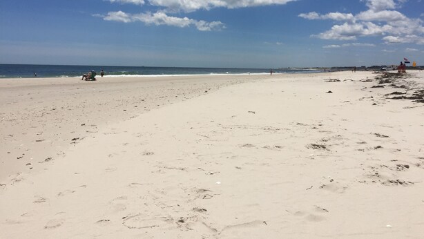 A wide sandy beach with footprints and a few people in the distance. - Stunning 3BR, 2BA penthouse 5 blocks from lighthouse. Last week open 8/16-23! (Barnegat Light)