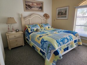 A bedroom with a bed, a nightstand, a lamp, and two wall-mounted paintings.