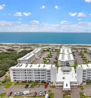 Un hotel de varios pisos con un patio central, estacionamiento y vistas al océano.