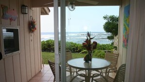 A covered patio with a round table and chairs, overlooking the ocean. - Beautiful Ocean/Beachfront Property and A Private Back Yard!  AC in both BDRMS! (Kailua-Kona)